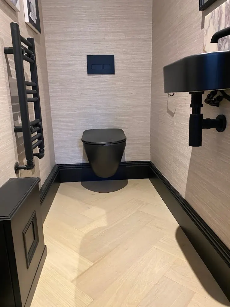 Compact cloakroom with black wall-hung toilet, black basin and herringbone floor
